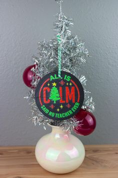 a christmas ornament on top of a white vase filled with balls and tinsel