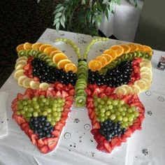 a butterfly made out of fruit on top of a white paper plate with the words seasonal food art kitchen decor