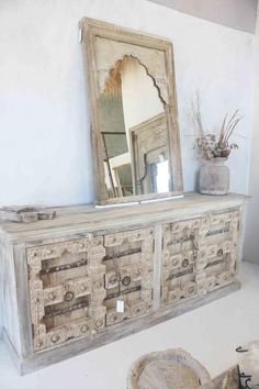 an old dresser with mirror and vases on top