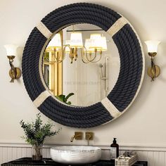 a round mirror hanging on the side of a wall next to a sink and lamp