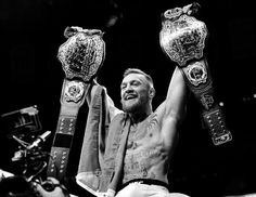 a man sitting on top of a motorcycle holding up two large metal objects in the air