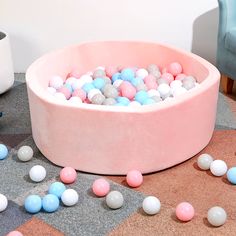 a pink bowl filled with balls on top of a floor next to a blue chair