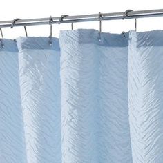 a white shower curtain hanging from a metal rod