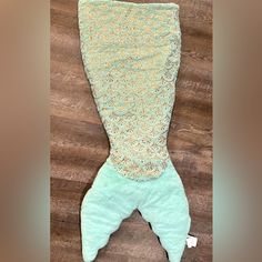 an image of a mermaid tail made out of material on the floor in front of a wooden background