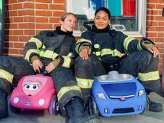 two women in firefighter gear sitting on the ground next to their children's toys