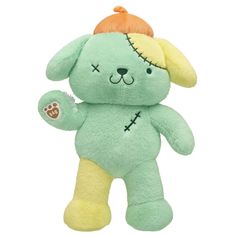 a green teddy bear with an orange hat on it's head and arms, standing upright