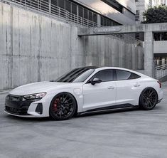 a white sports car parked in front of a building with black rims and red brake pads