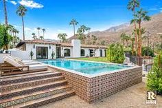 an outdoor swimming pool with steps leading up to it and palm trees in the background