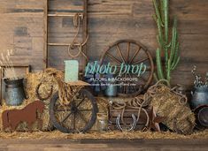 an old fashioned farm scene with hay and other items on display in front of a wooden wall