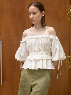 This product is an Off-Shoulder String Blouse, elegantly crafted to showcase a balanced blend of contemporary style and romantic detailing. It features adjustable string ties at the shoulders for a customizable fit and a cinched waist that enhances the silhouette. The ruffled overlay at the chest and arms adds a dynamic, flowing appearance to the garment. - This Off-Shoulder String Blouse is designed with adjustable shoulder ties that provide both support and a delicate feminine touch.- The cinched waistline emphasizes the wearer’s figure while offering a comfortable fit.- Ruffle accents across the chest and arms introduce a playful and whimsical flair to this fashionable piece.- Constructed from a lightweight fabric, this blouse is ideal for warm weather, providing breathabilit Elegant Tops With Tie Straps For Day Out, Elegant Off-shoulder Top With Smocked Bodice, Elegant Tops With Tie Straps, Elegant Off-shoulder Top For Spring Brunch, Elegant Spring Off-shoulder Top For Brunch, Feminine Off-shoulder Top For Brunch, Elegant Off-shoulder Tops For Daywear, Elegant Off-shoulder Top For Day Out In Spring, Elegant Off-shoulder Top For Spring Day Out