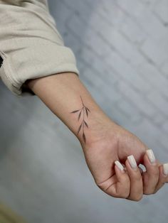 a woman's hand with a small tattoo on the left side of her arm