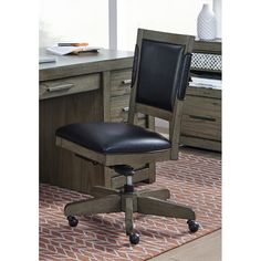 an office chair with black leather upholstered seat and casteors sits in front of a desk