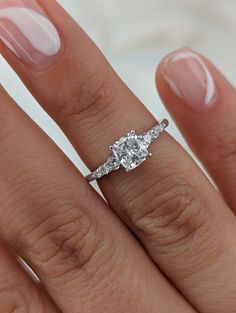 a woman's hand with a diamond ring on top of her finger and an engagement band