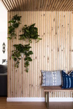 a living room with wooden slats and plants on the wall behind a wood bench