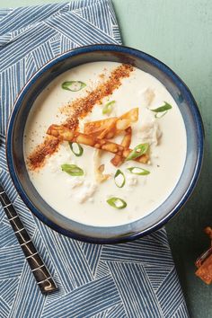 a blue bowl filled with soup on top of a blue and white cloth next to a spoon