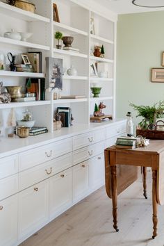 a room filled with lots of white furniture and shelves full of books on top of them