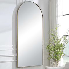 a mirror sitting on top of a white table next to a plant in a vase