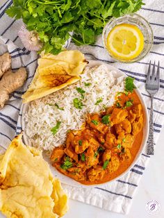 a white plate topped with rice and chicken next to cilantro, tortilla chips and lemon wedges