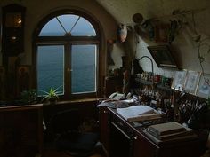 a room filled with lots of clutter next to an open window overlooking the ocean