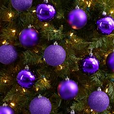 purple christmas ornaments are hanging from the tree