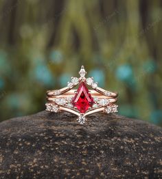 a red diamond ring sitting on top of a rock