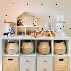 a shelf with baskets and toys on top of it in a child's room