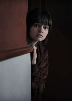 a woman leaning against a wall in the dark