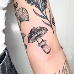 a black and white photo of a mushroom tattoo on the left arm with flowers around it