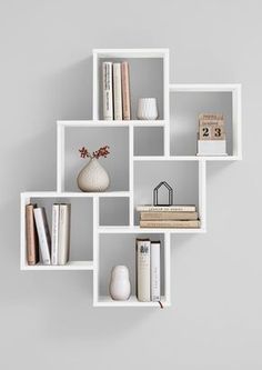 a white shelf with books and vases on it