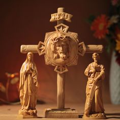 three wooden figurines stand in front of a cross with the image of jesus on it