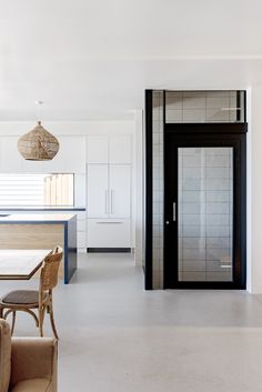 an open kitchen and living room with white walls, flooring and furniture in it