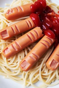 four hotdogs with ketchup and noodles on a plate