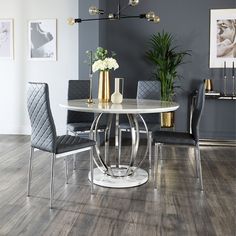 a dining room table with white chairs and gold vases on it's centerpiece