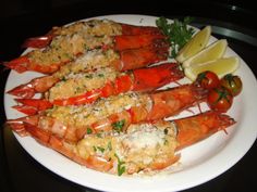 cooked lobsters on a white plate with lemon wedges and parmesan cheese