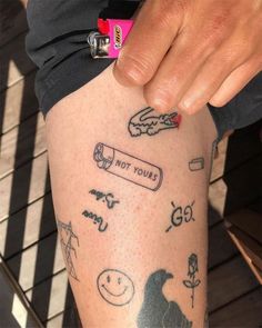 a person with tattoos on their legs holding onto a cell phone and some other items