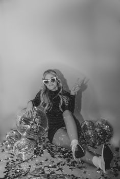 a woman sitting on top of a bed surrounded by confetti and disco balls