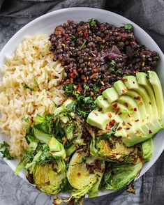 a white bowl filled with rice, beans and avocado on top of a table