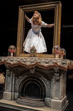 a woman standing on top of a fireplace in front of a mirror