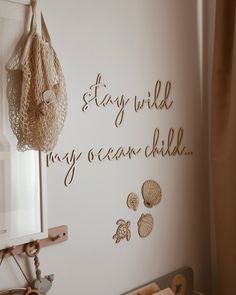 there is a sign that says stay wild, my ocean child on the wall next to some seashells