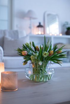 a vase filled with flowers sitting on top of a table next to a lit candle