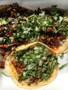 three tacos with meat, onions and herbs on them