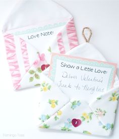 two envelopes with love notes attached to them on a white surface, next to each other