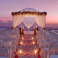 the aisle is decorated with candles and flowers for an outdoor wedding ceremony on the beach