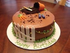 a birthday cake with carrots and dirt in the shape of a fence on a wooden table