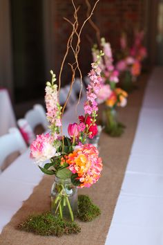 flowers are in vases with moss on the table