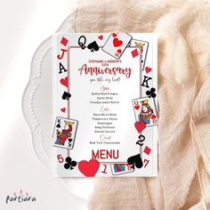 a white plate topped with a card game wedding anniversary dinner menu design on top of a table cloth