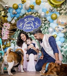 a man and woman pose for a photo with their two dogs in front of balloons