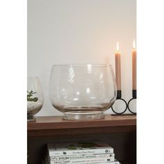 a glass bowl sitting on top of a wooden table next to two candles and books