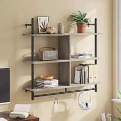 a computer desk with books and headphones on it next to a wall mounted shelf