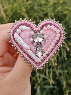 a pink heart shaped brooch with pearls and crystals on it's center piece